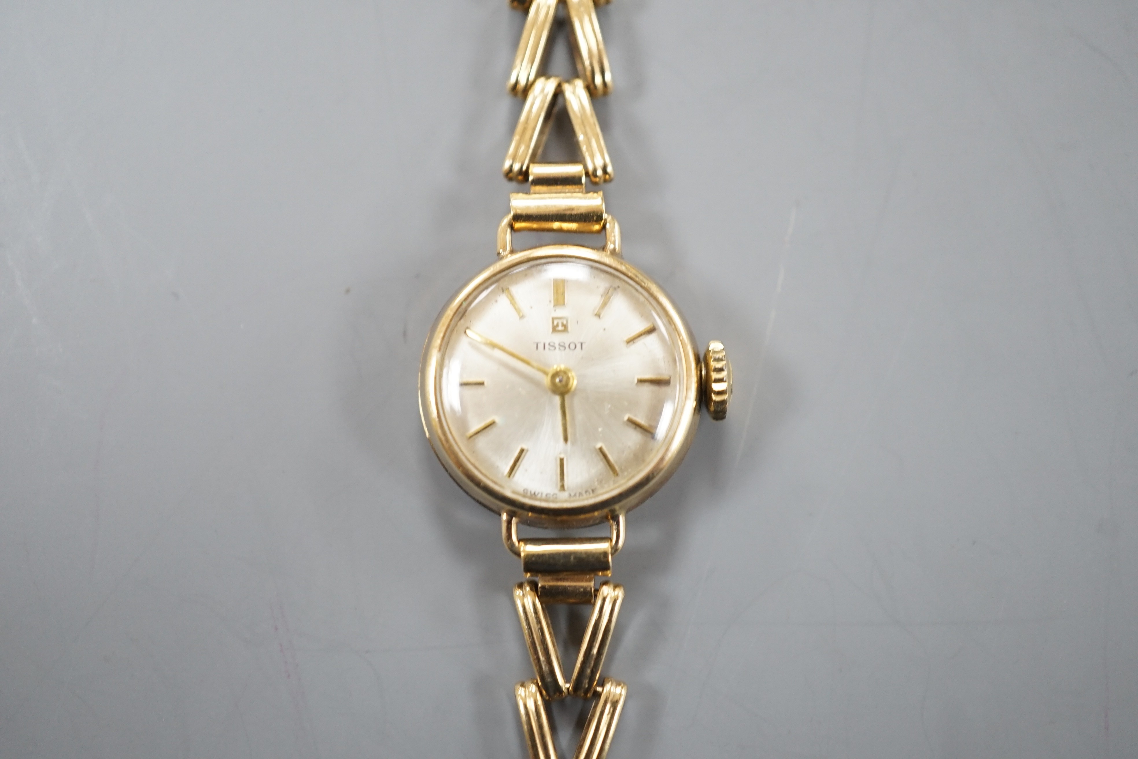 A lady's 9ct gold Tissot manual wind wrist watch, on a 9ct gold bracelet, overall length 16.25cm, gross weight 11.2 grams.